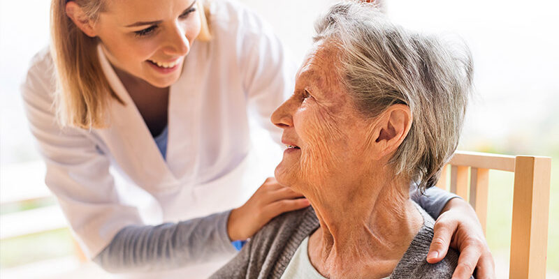 Pflegerin spricht mit alter Frau